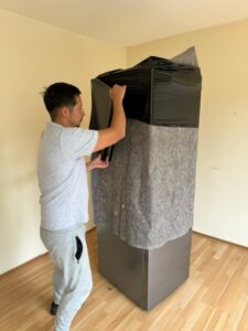 Man wikkelt koelkast en beschermdoek in met rekfolie